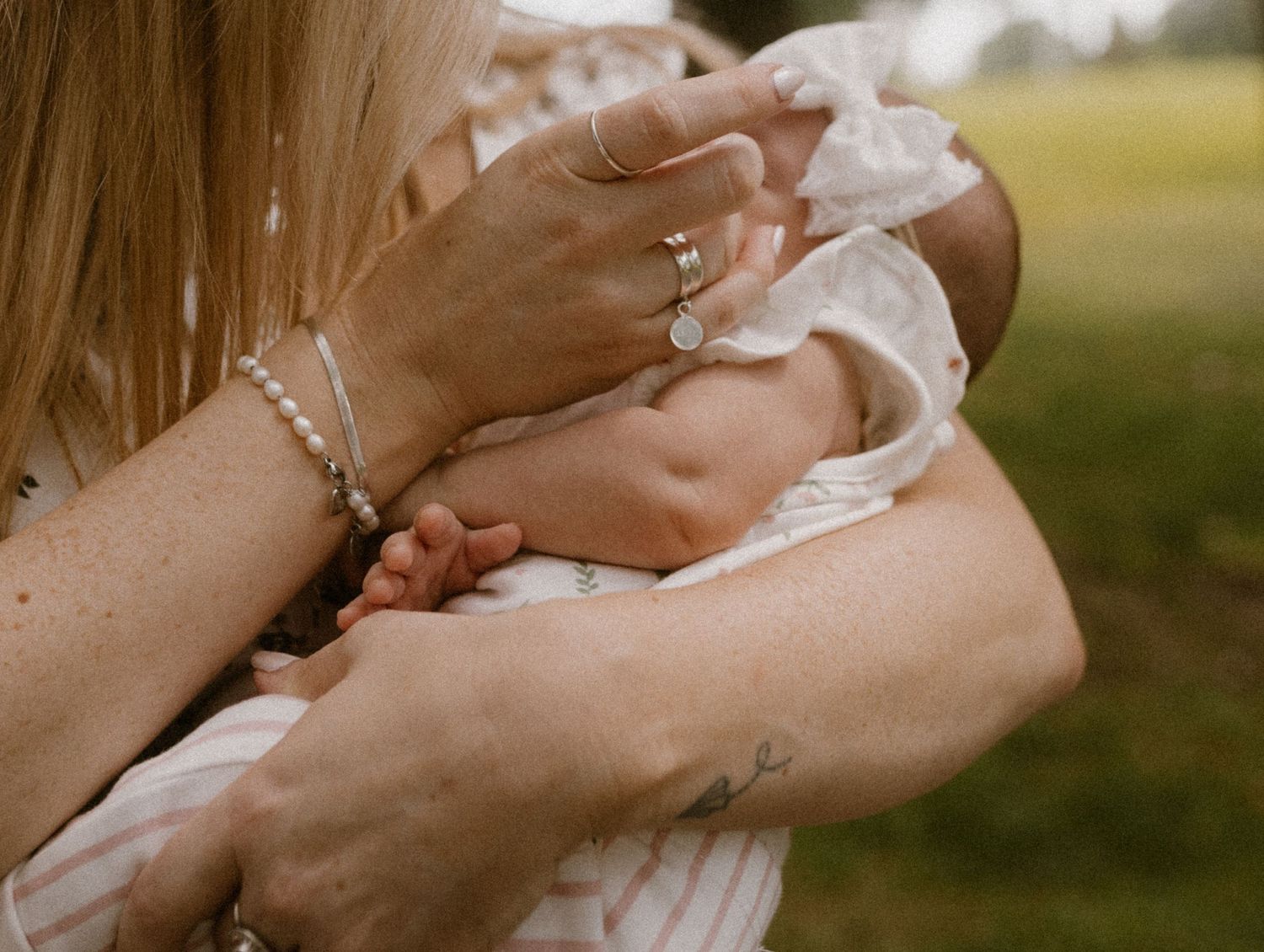Close-up of hands holding a sleeping baby wearing white clothing.
