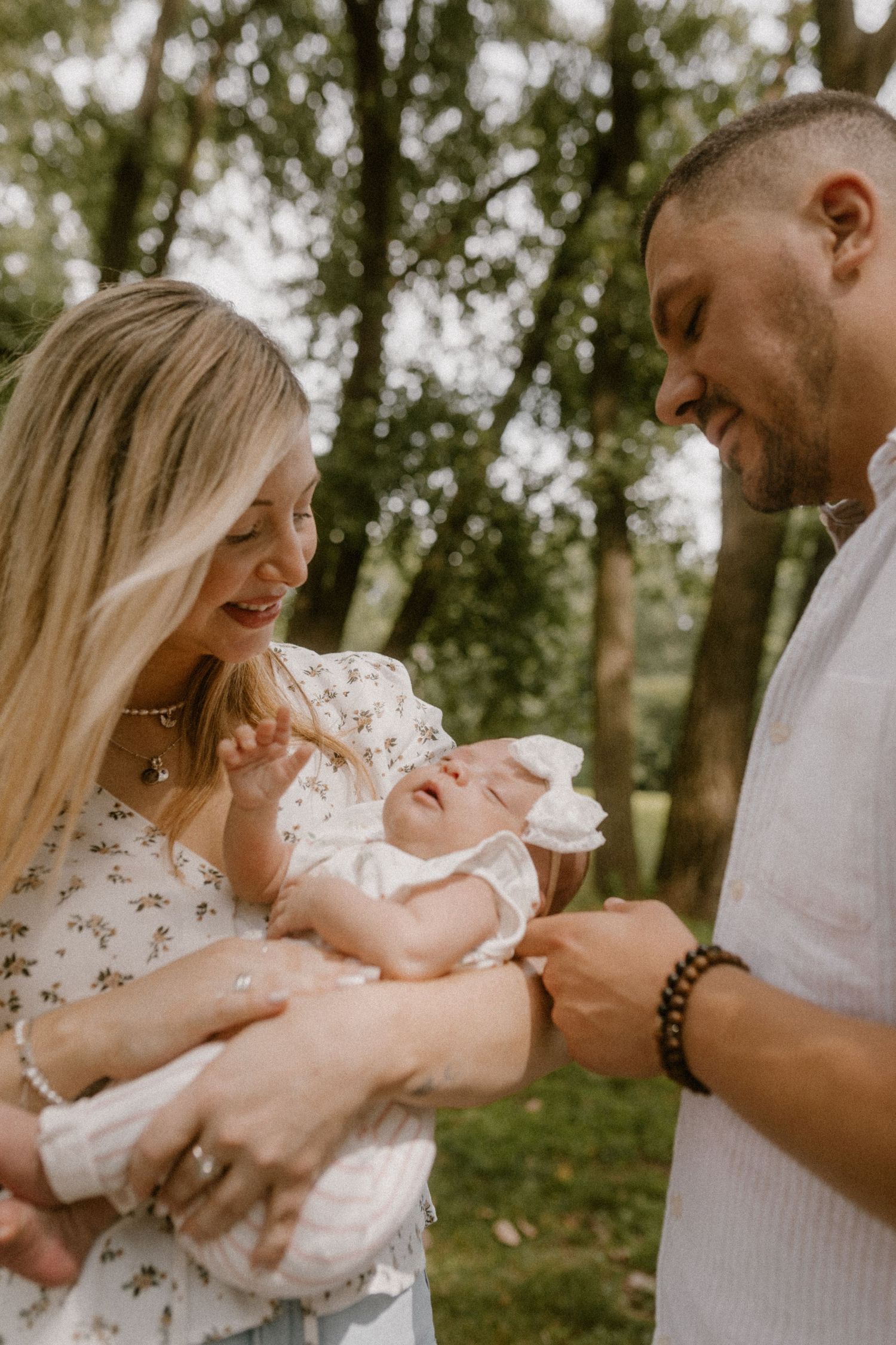 A family shares a tender moment together in a wooded park setting.