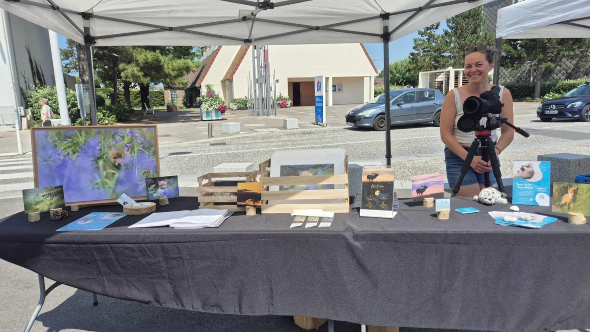 Outdoor vendor booth with photography prints and materials displayed on a black tablecloth.