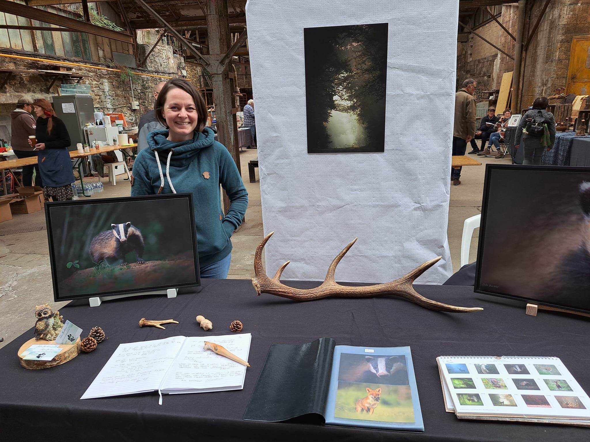 Photography display booth with nature prints, antlers, and artwork arranged on a black tablecloth.