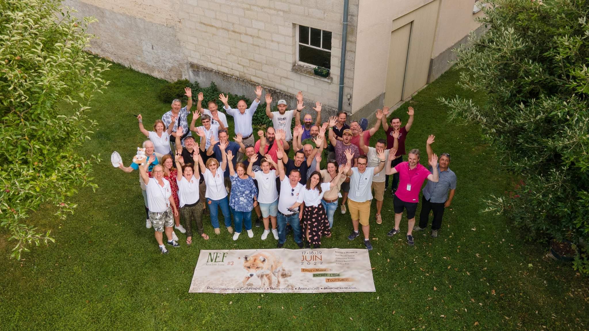 Group photo of workshop participants gathered outdoors near a white building.