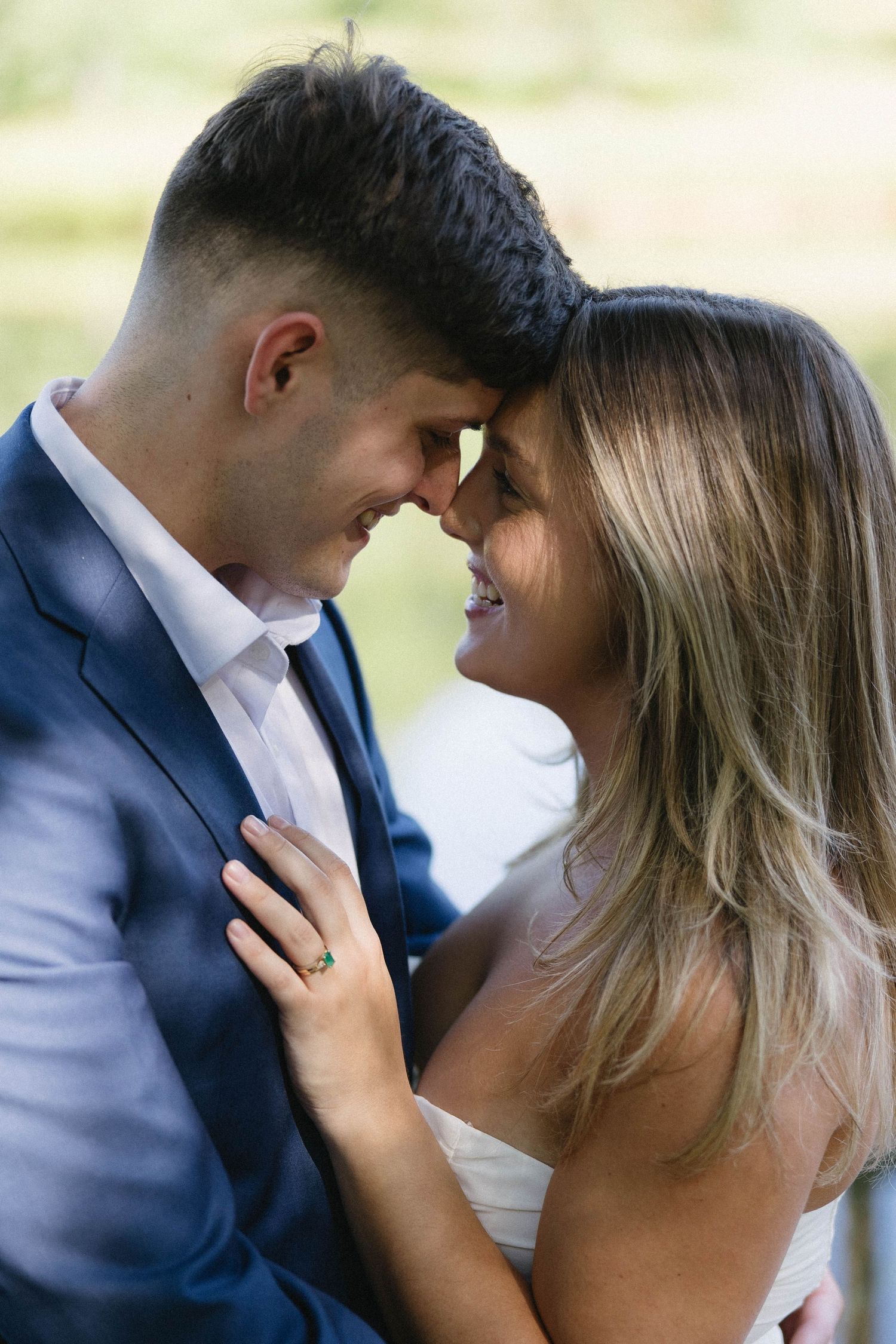 A romantic moment captured between a couple in wedding attire as they share an intimate close-up outdoors.