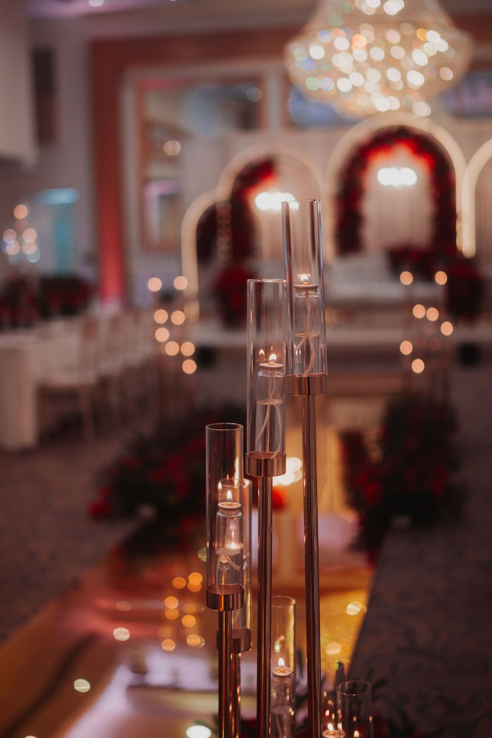 Tall glass cylinder candle holders create an elegant ambiance in a dimly lit reception venue.