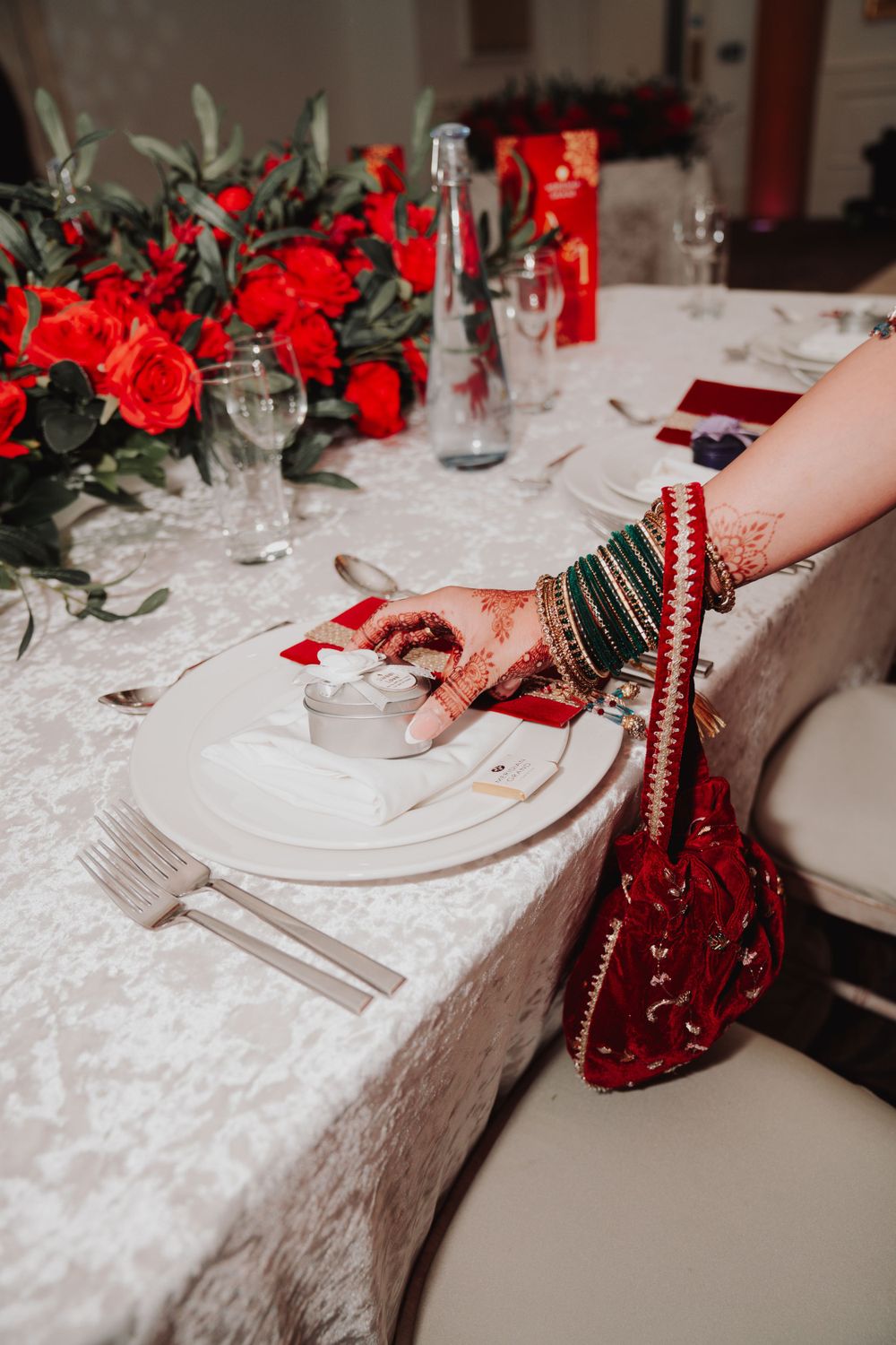 Decorated table setting with red roses and traditional bangles visible in the foreground.