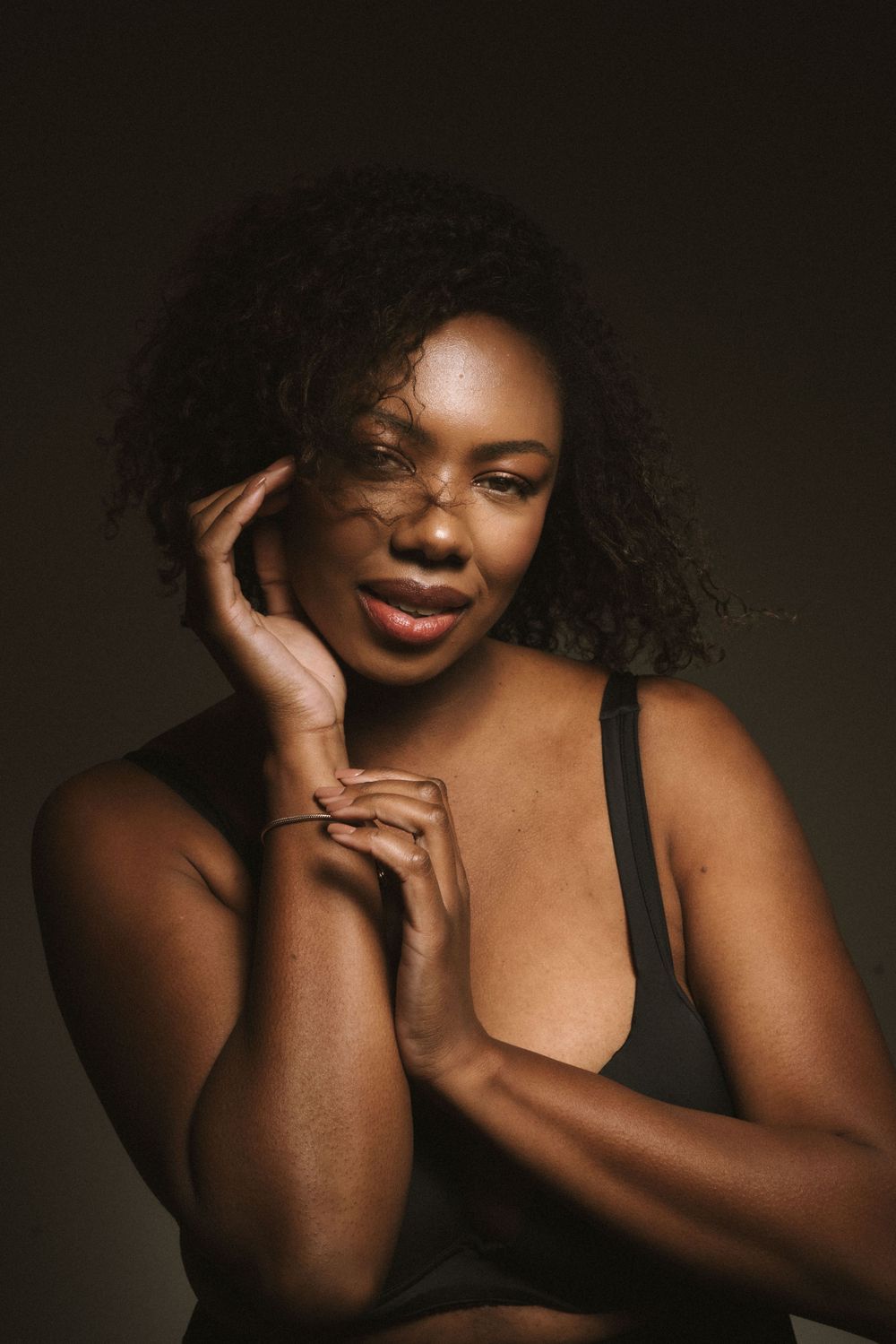 Warm toned beauty portrait against dark background with natural lighting.