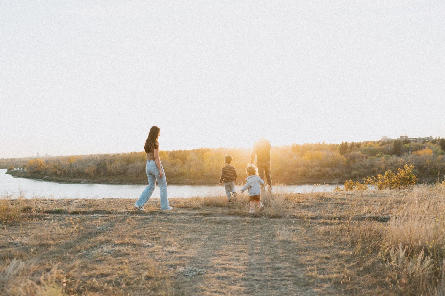 Family strolling along a scenic path near water during sunset.