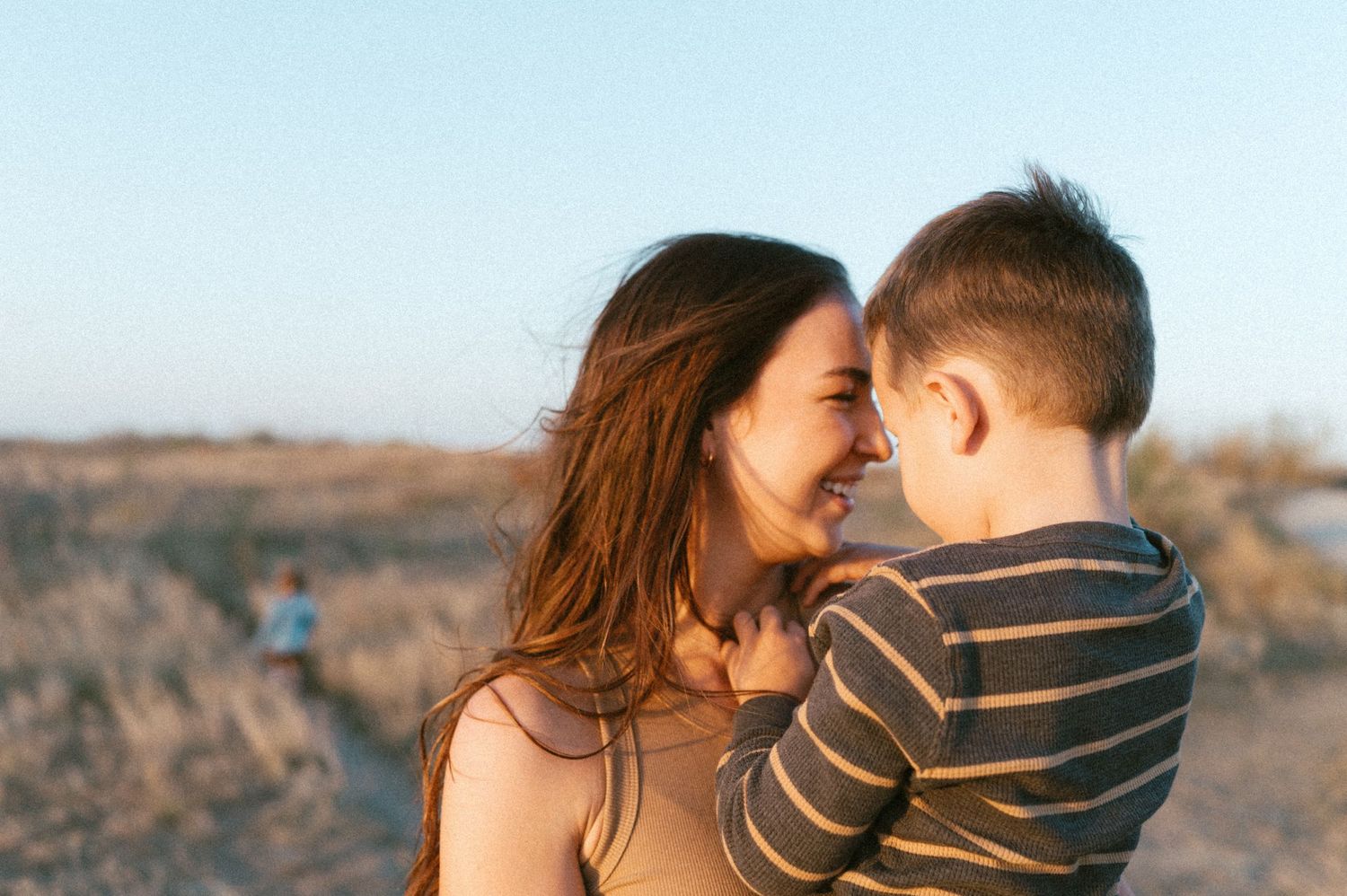 Tender family moment shared between parent and child against natural desert backdrop.