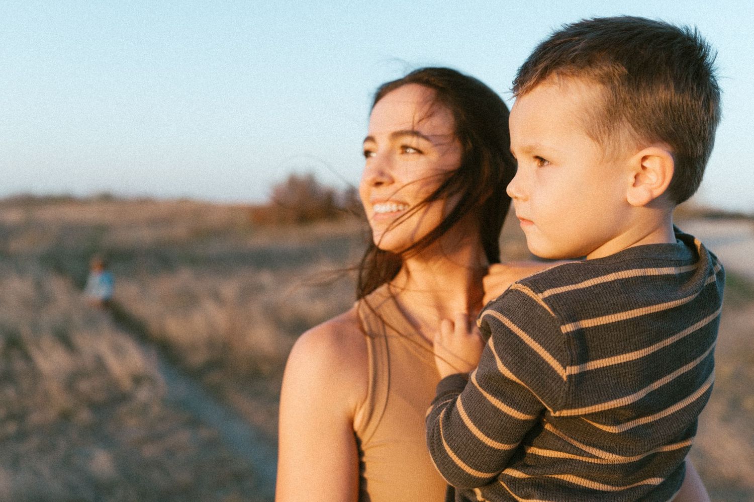 Candid outdoor portrait of parent and child enjoying sunset in nature.