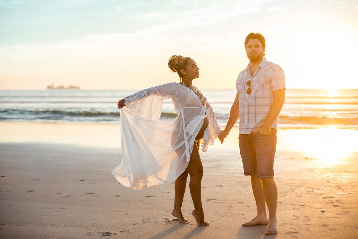 Parents-to-be holding hands with beautiful sunset in a serene Melbourne beach maternity shoot