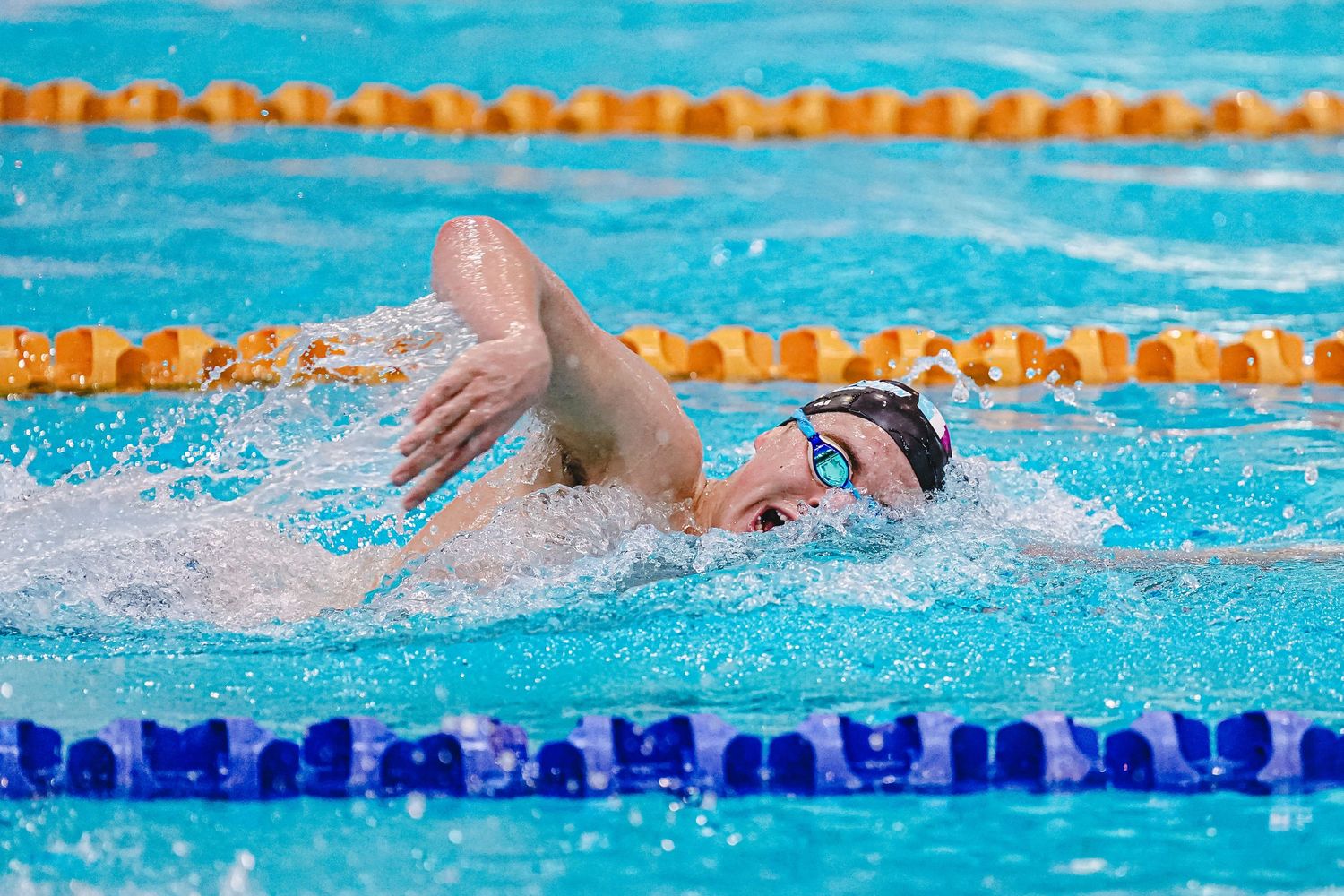 Competitive swimmer performs breaststroke in swimming pool lane during training session.