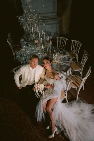 A bride and groom share an intimate moment in chairs surrounded by candlelight at their evening wedding reception.