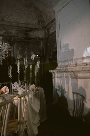 Elegant crystal candelabras and soft fabric drape a formal dining table in a dimly lit vintage room with ornate moldings.