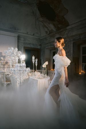Ethereal bridal sequence shows flowing white gown against crystal chandeliers in dimly lit elegant interior space.