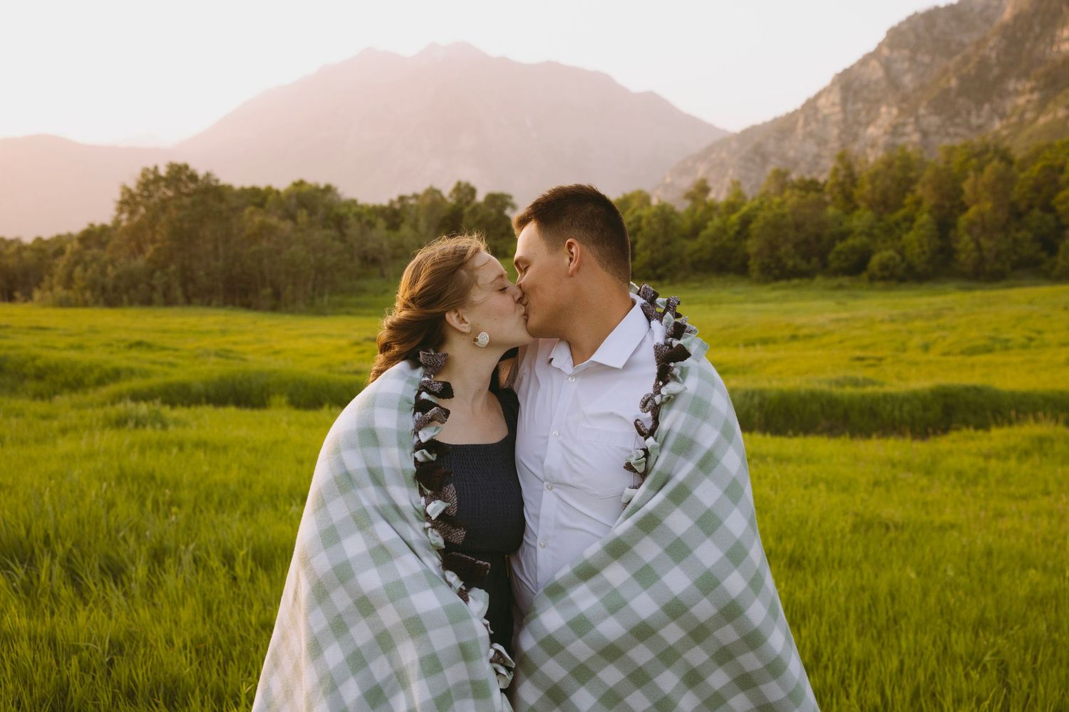 Close-up of autumn-themed bridal bouquet with peach dahlias, orange roses and greenery against a white wedding dress.