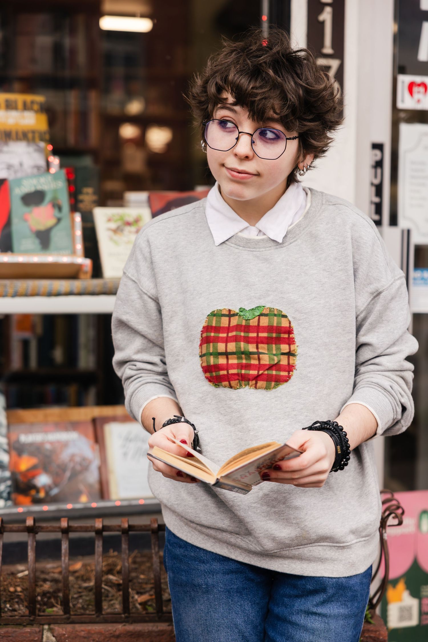 A collage of someone wearing a gray sweatshirt with a burger design while reading and browsing inside a shop.