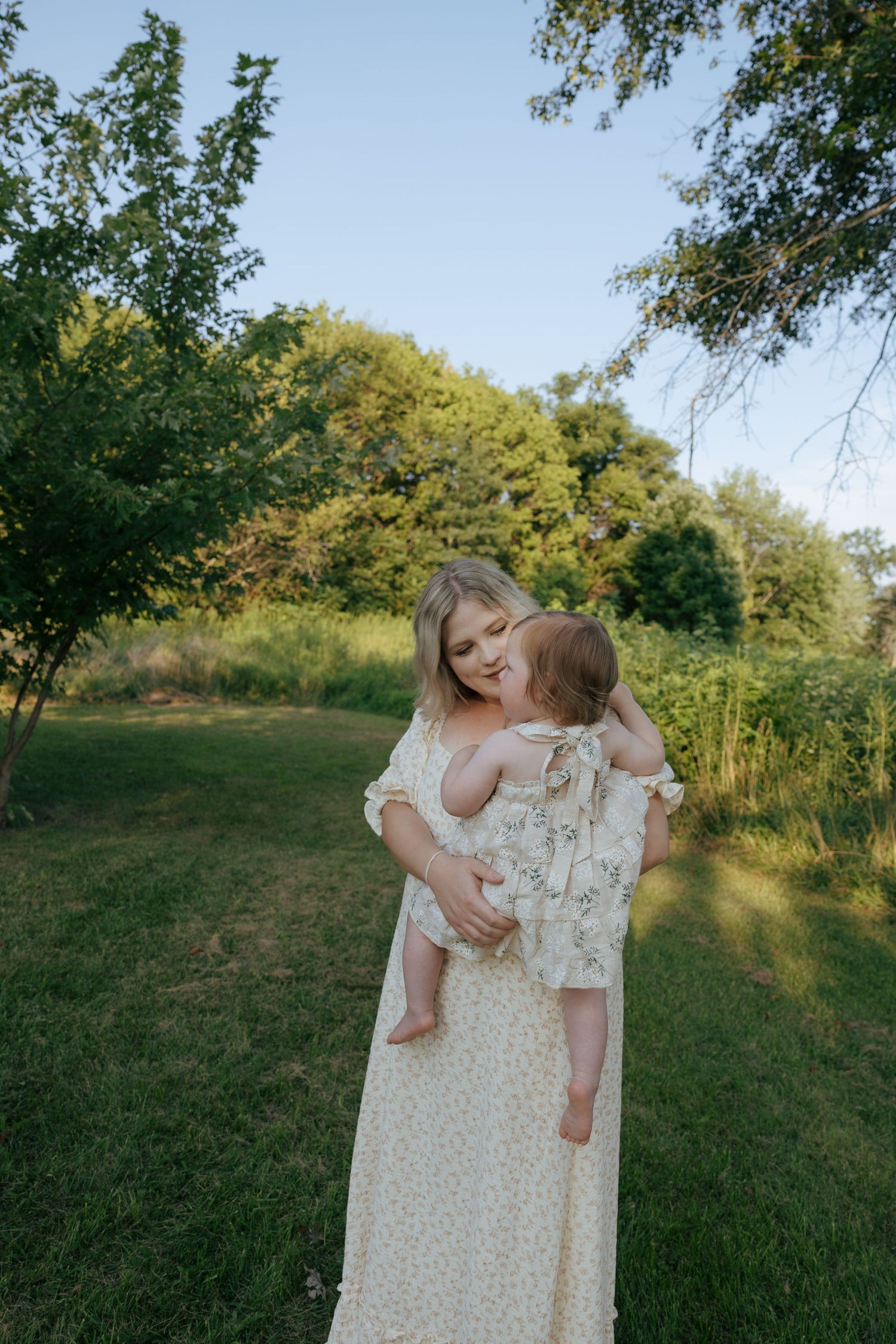 A parent and child share a joyful moment together while playing outdoors in a park setting during golden hour.