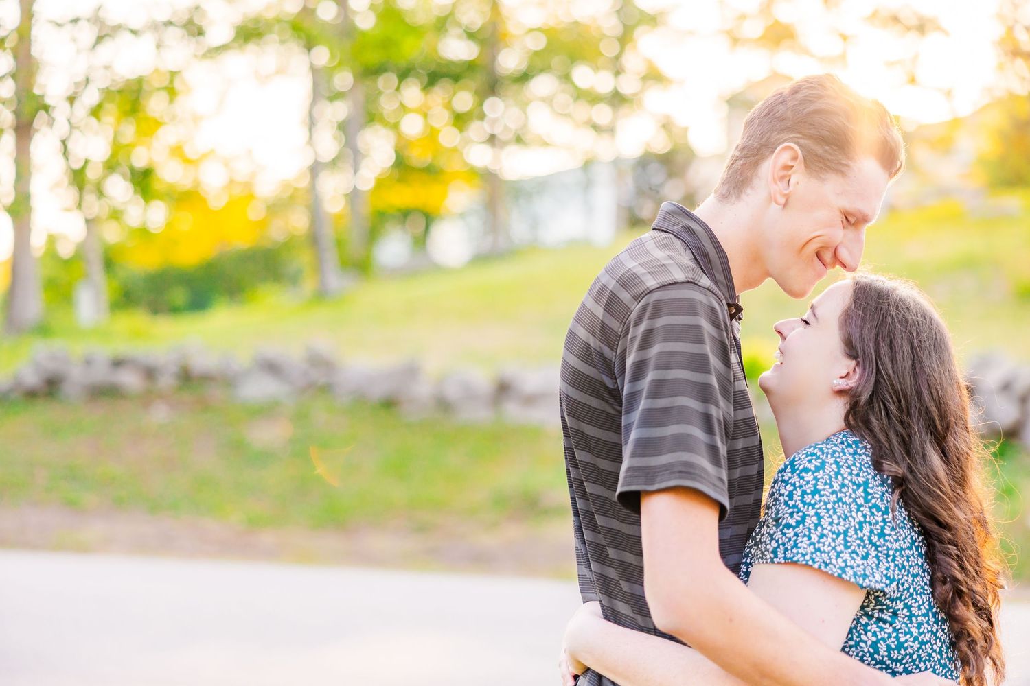 A couple gazes at each other lovingly on a hilltop with scenic mountain and lake views in the background.