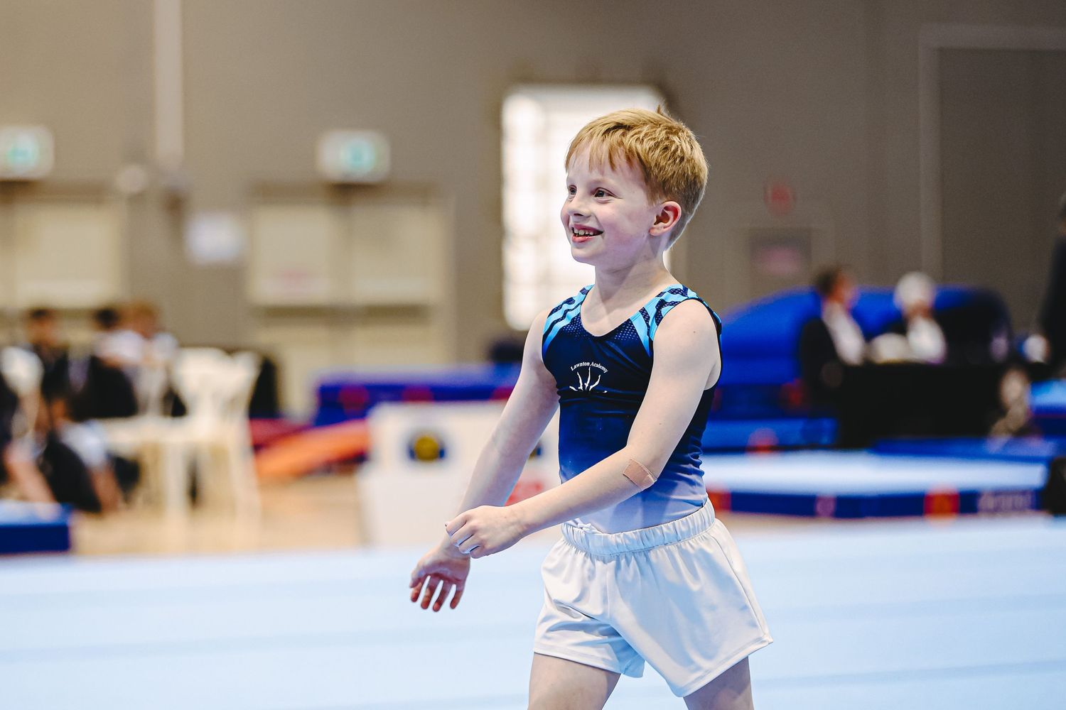 A young gymnast performs a graceful split handstand on the balance beam during competition practice.