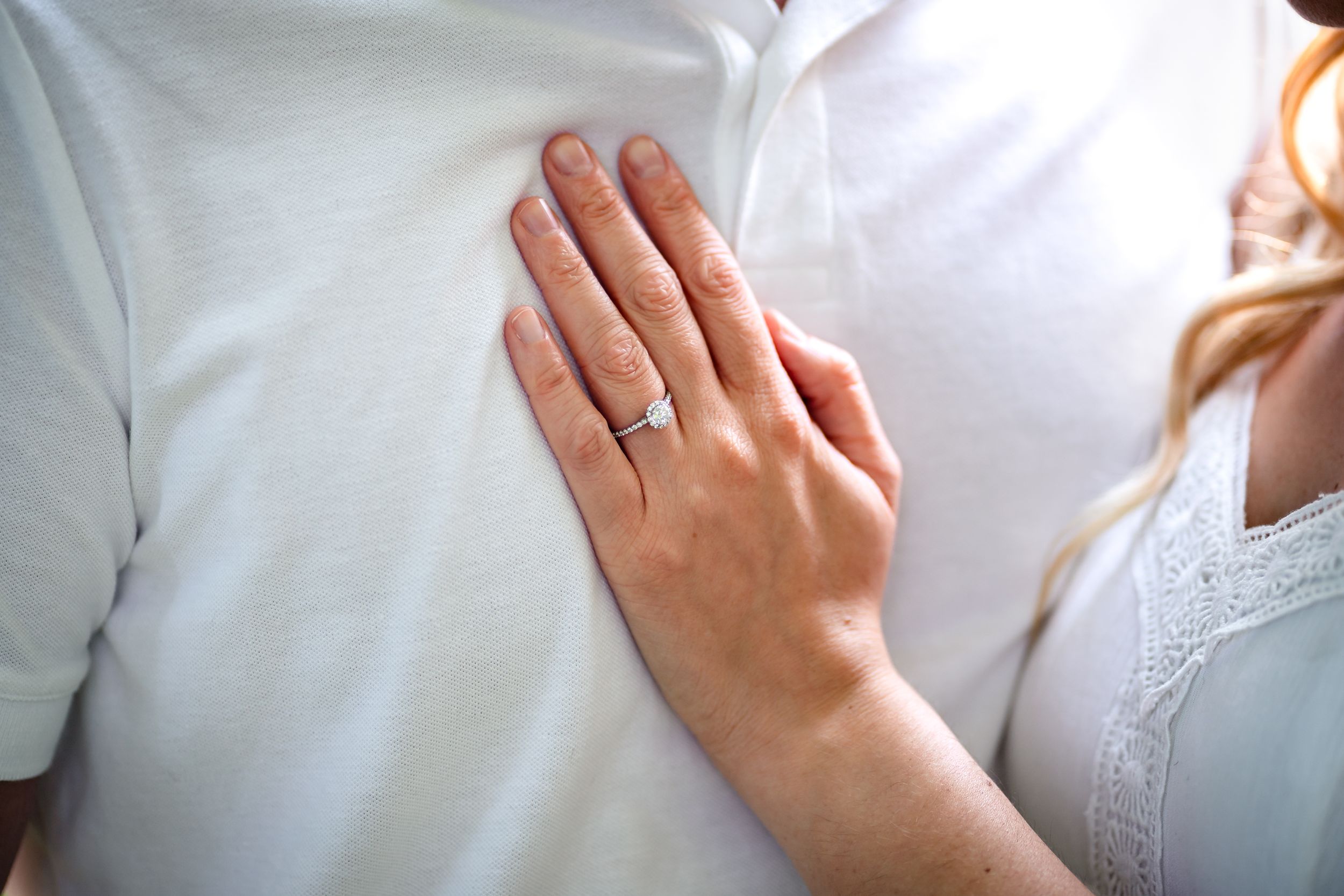 Close-up detail shot of hands and white clothing during an intimate moment.