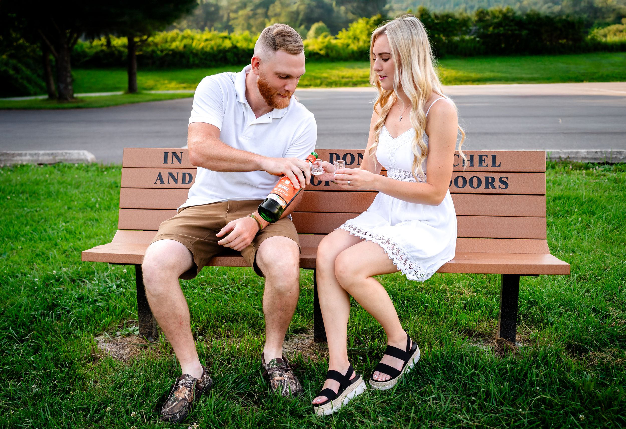 Couple sitting together on a wooden bench in a lush green park setting.