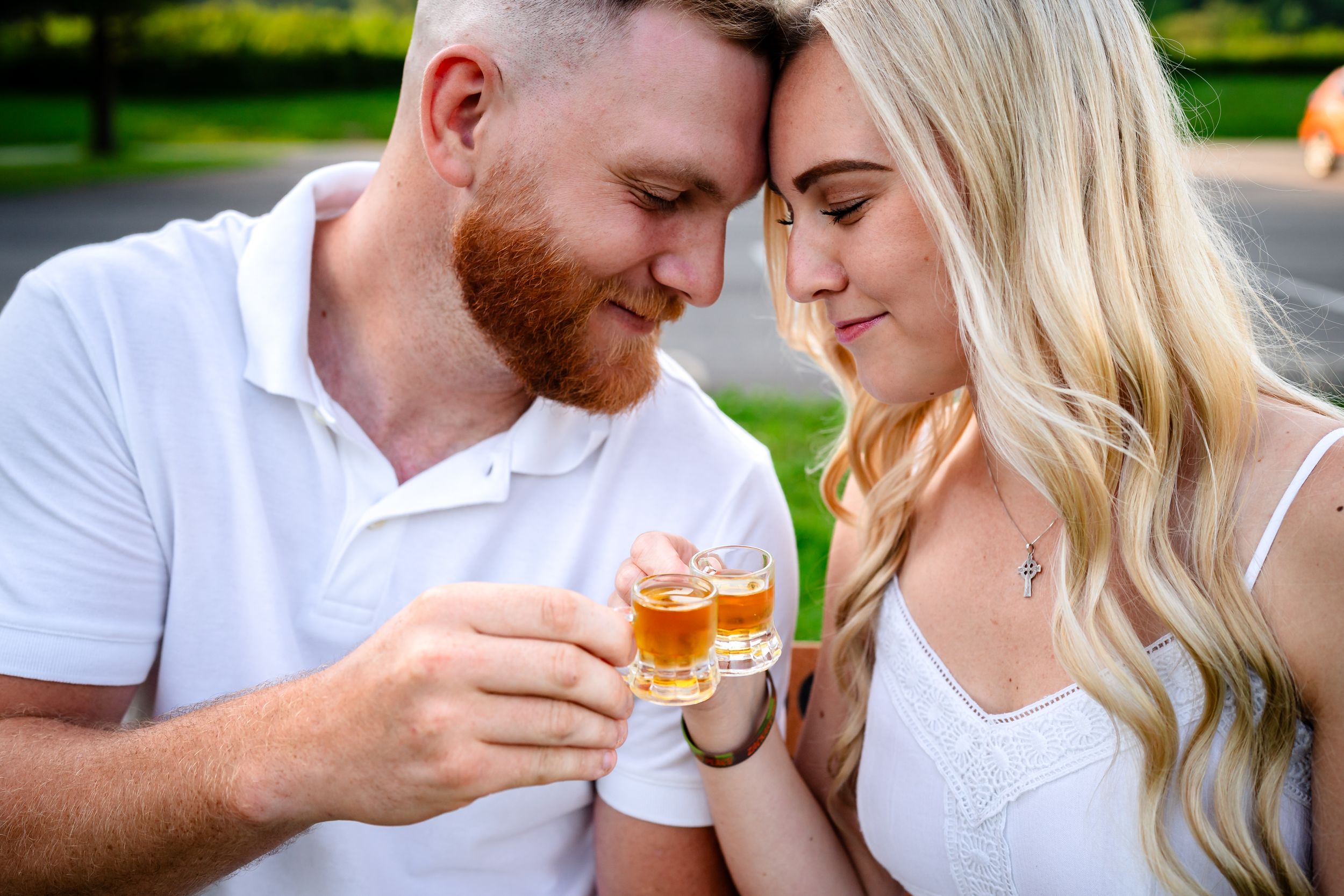 Romantic couple sharing drinks while sitting close together outdoors.