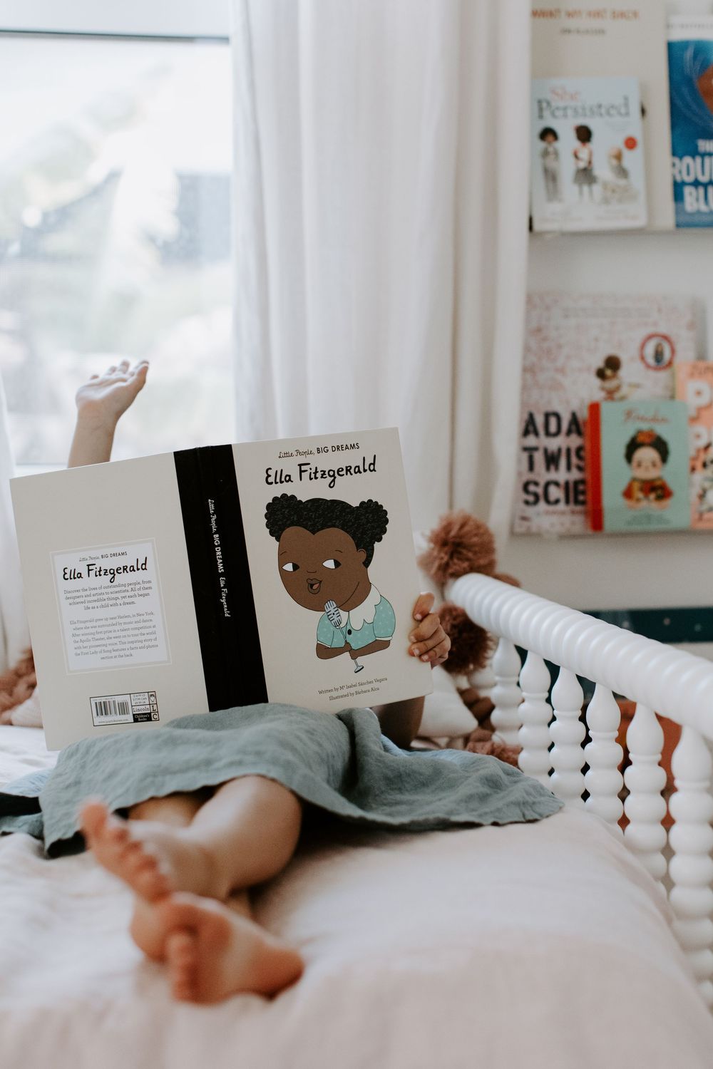 Reading time in bed with children's books displayed on floating shelves in background.