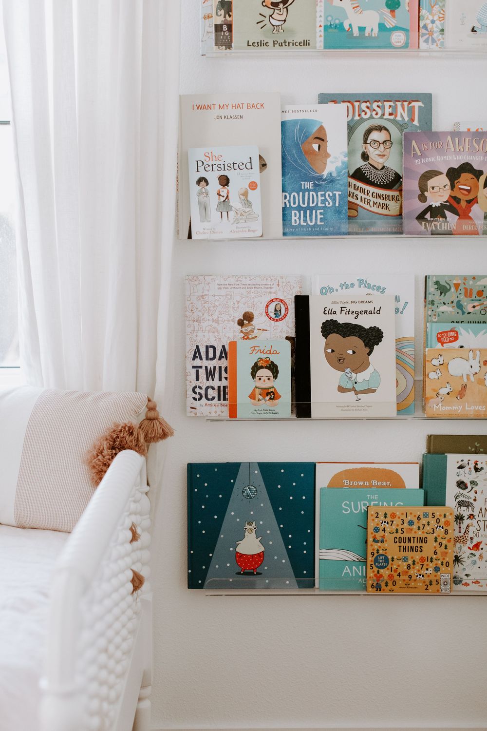 Children's book display on white shelves featuring diverse and educational titles.