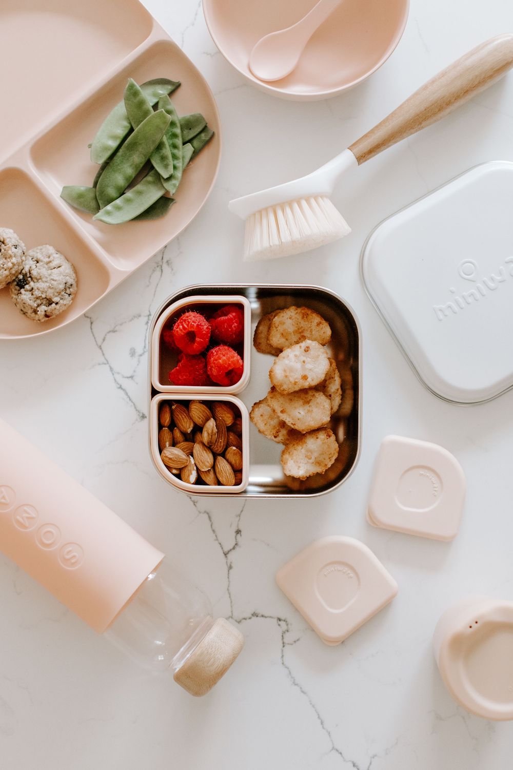 Organized lunch containers with healthy snacks on marble countertop.
