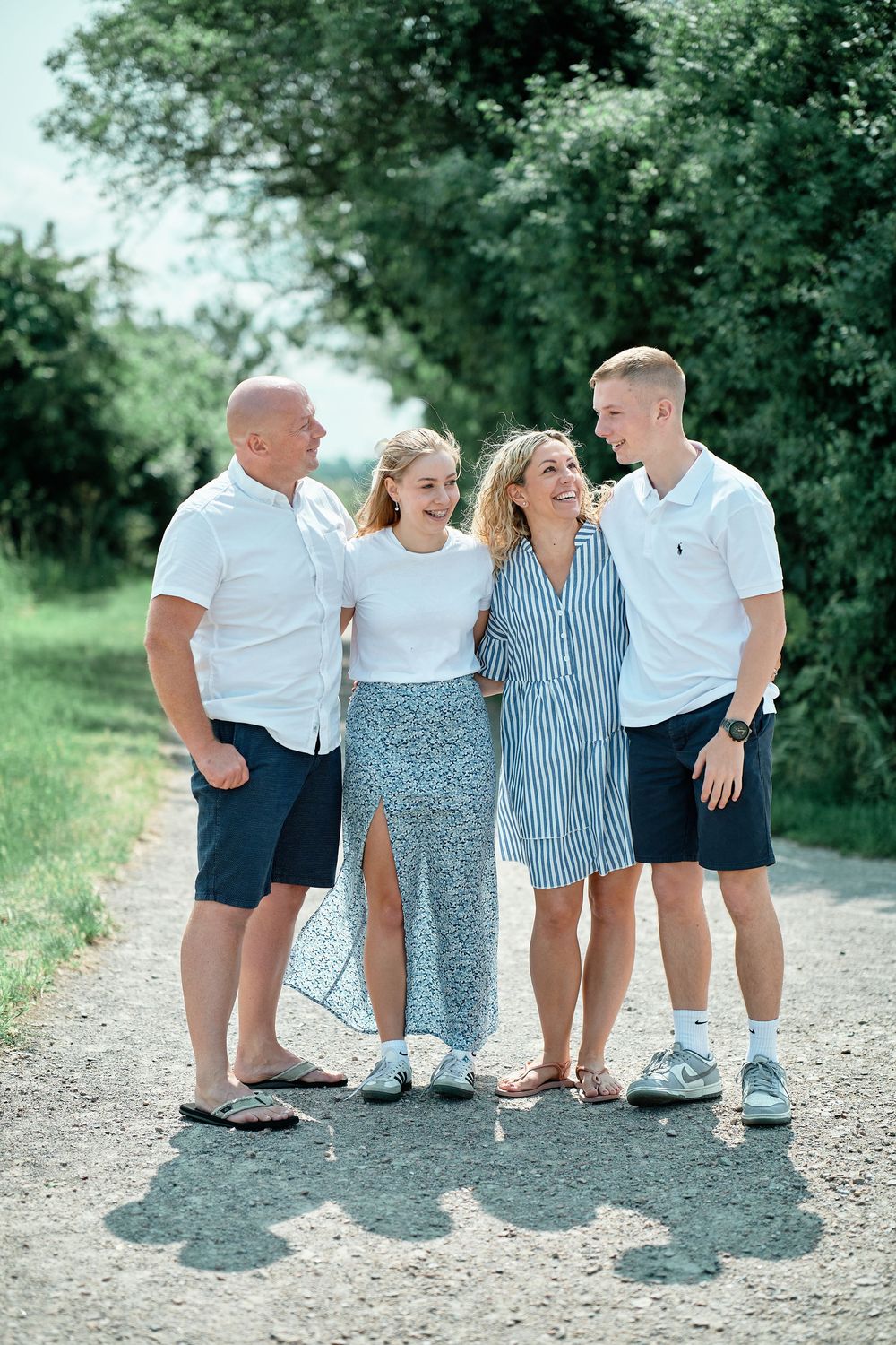 A group of young ones in coordinated blue and white summer outfits stand together on a dirt path in a park.