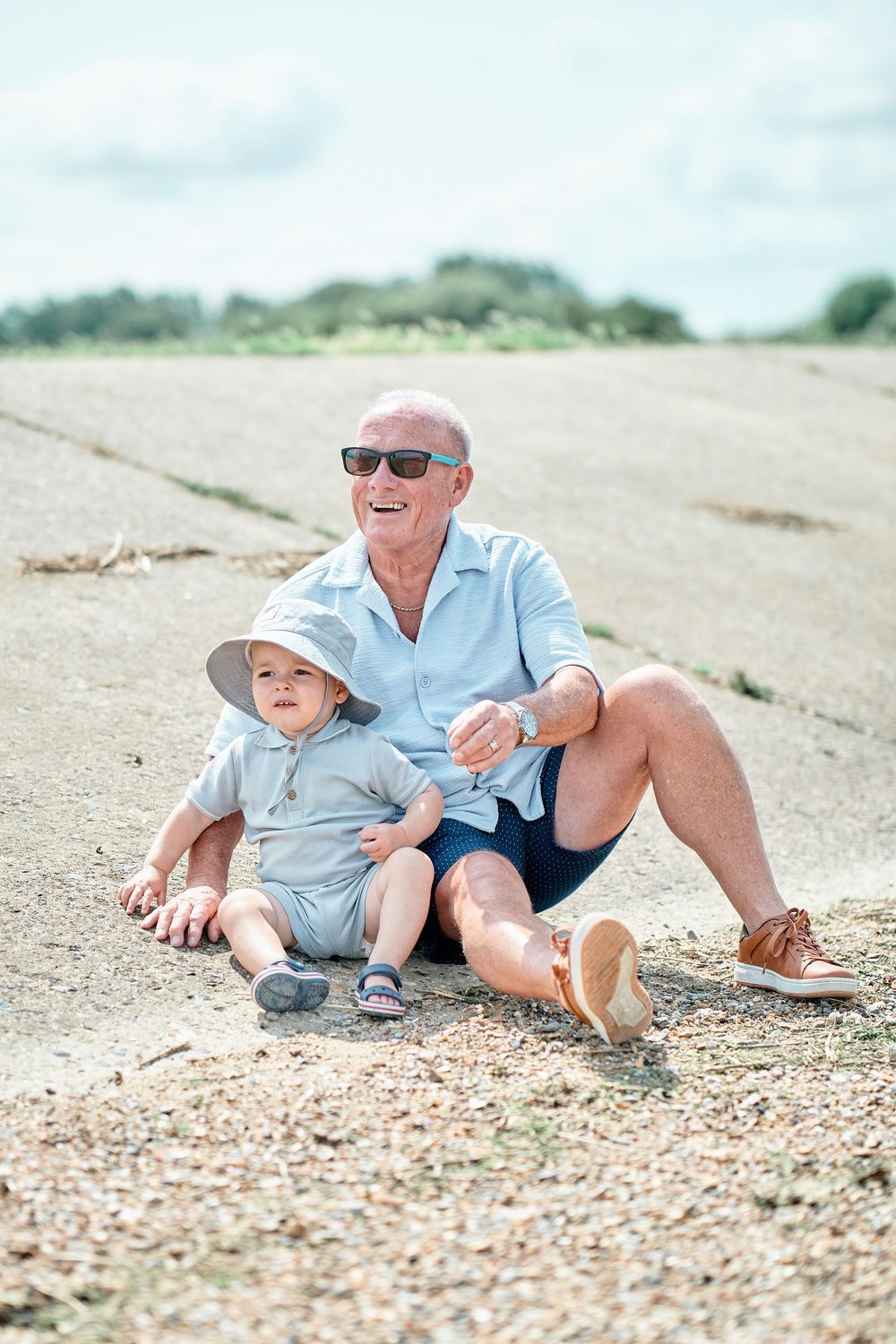 People relaxing on a sandy beach with shells and pebbles on a sunny summer day.