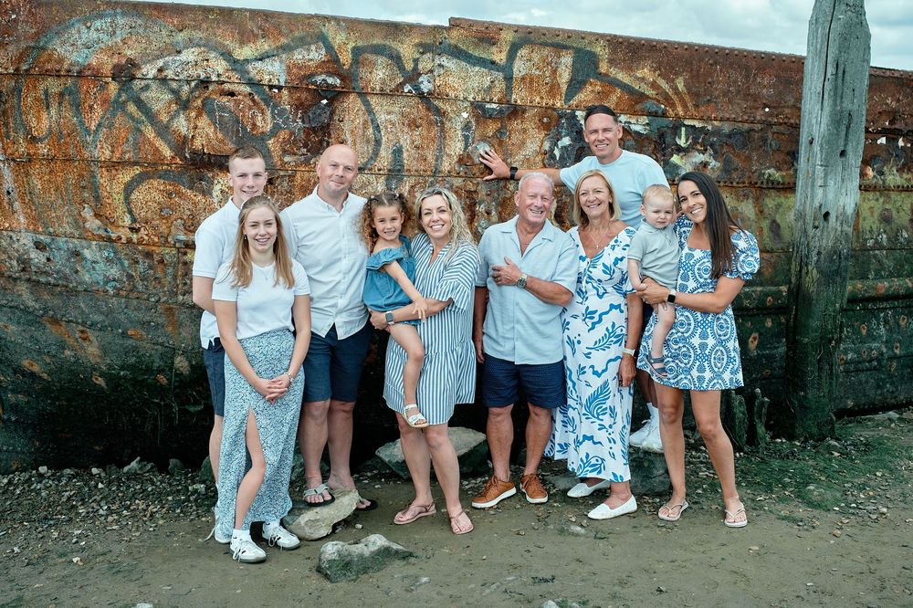 A group poses together in front of a graffiti-covered brick wall on a summer evening.