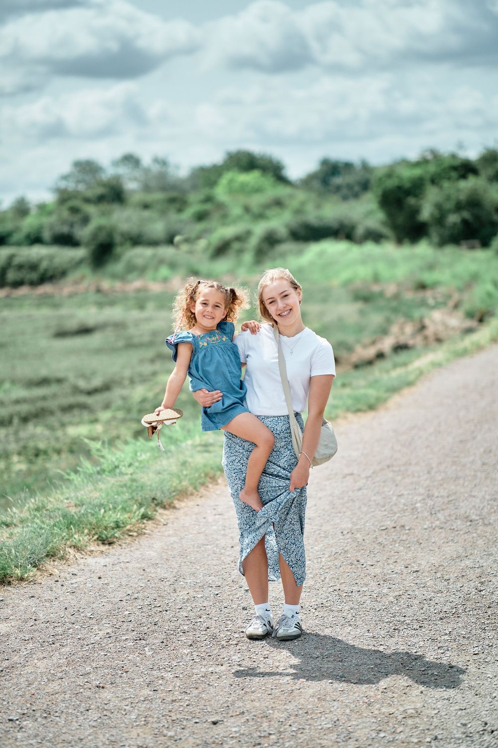 Candid outdoor photo shoot showing joyful interactions on a dirt path with scenic green hills in the background.