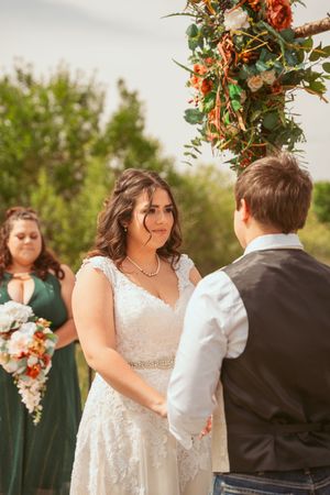 A romantic outdoor wedding ceremony with autumn-colored floral decorations and emerald bridesmaid dresses.