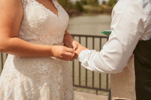 Close-up of hands exchanging rings during an outdoor wedding ceremony.