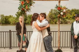 A romantic first kiss moment during an outdoor wedding ceremony by the water.