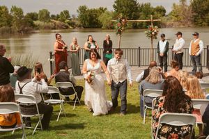 Guests seated at folding chairs enjoy a casual outdoor wedding reception near a waterfront.