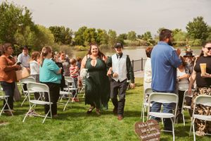 Wedding guests exit rows of white chairs on a lawn during an outdoor celebration.
