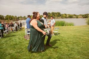 Wedding guests gather on a green lawn for an outdoor celebration near water.