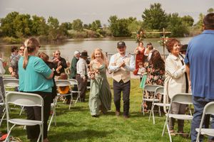 Guests gather on a grassy lawn during an outdoor wedding reception near a waterfront.