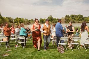 Group of wedding guests mingling outdoors in a casual setting with lawn chairs on a sunny day.