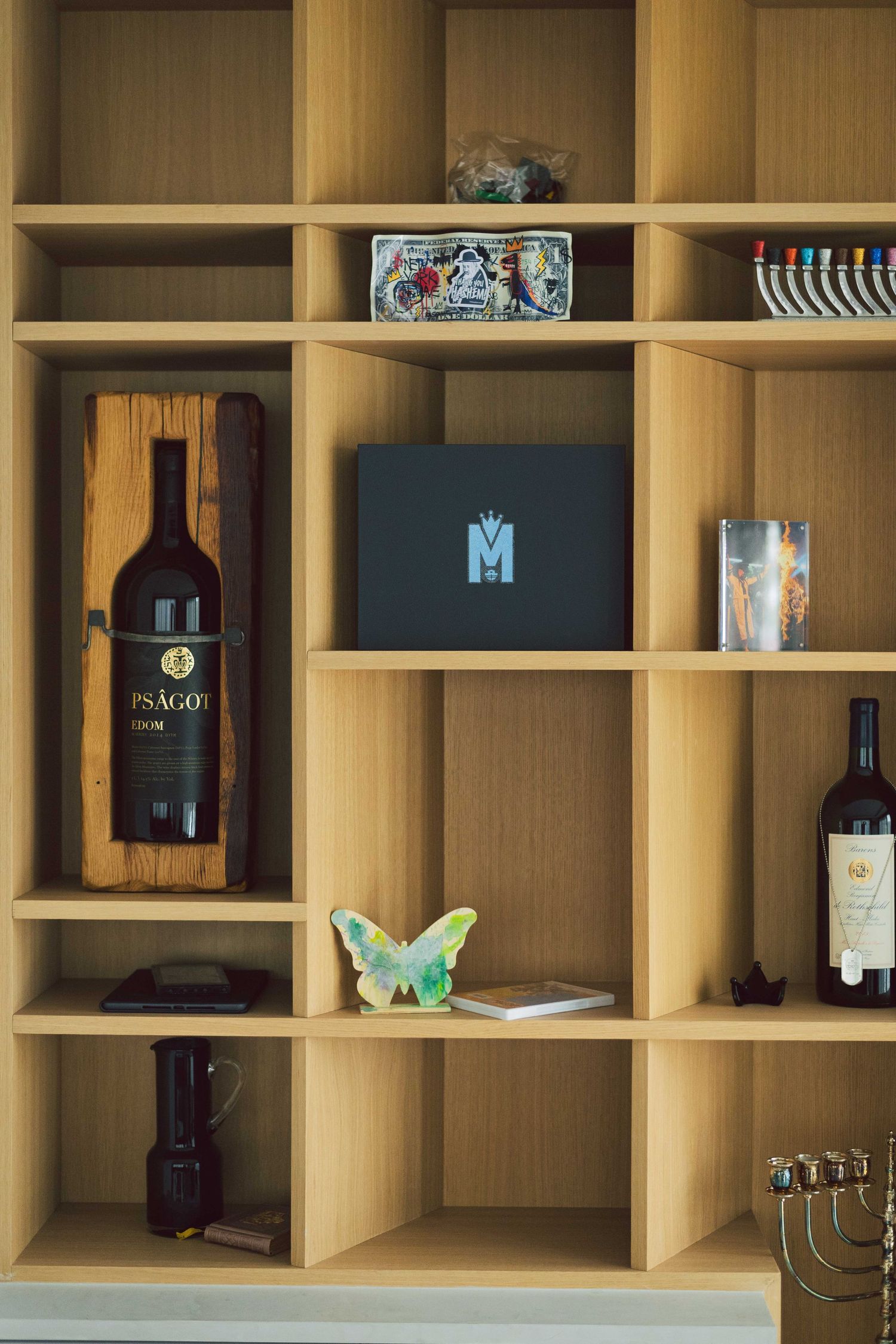 Modern wooden shelving unit displaying wine bottles and decorative items.