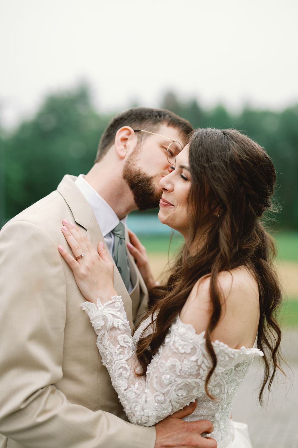 A tender moment shared between newlyweds in a romantic outdoor setting, wearing elegant wedding attire.