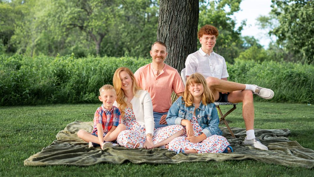 Family sitting together on the grass outdoors during the Conner family portrait session.