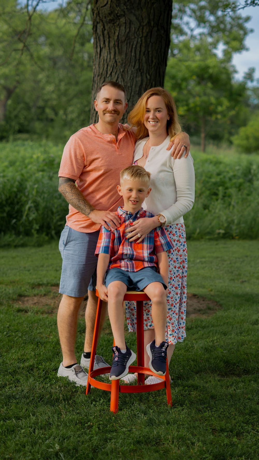 Parents standing with their child outdoors during a family portrait session.