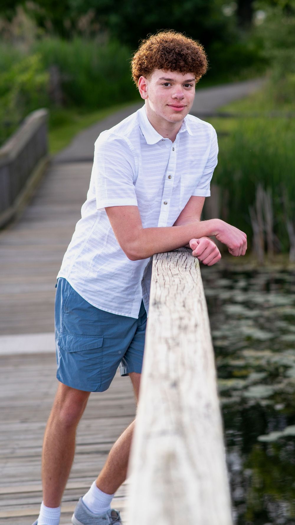 Teen boy standing outdoors near the water during a portrait session.
