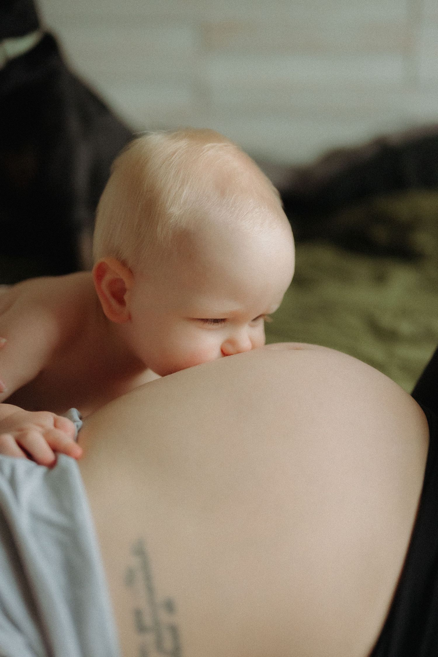 A sequence of tender maternal moments shows a small baby lovingly kissing a pregnant belly in an intimate setting.