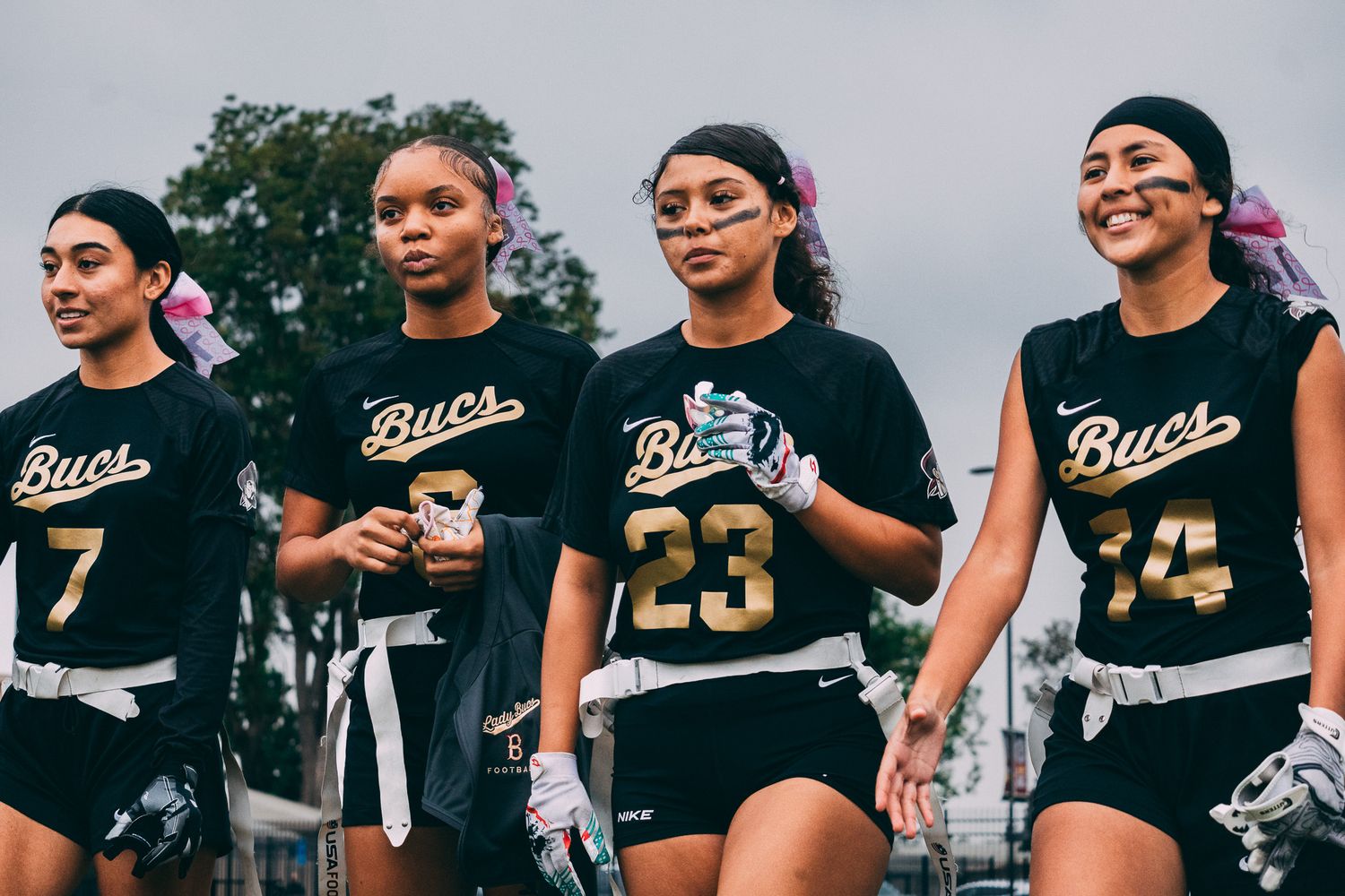 Row of athletes in black sports uniforms lineup side by side outdoors.