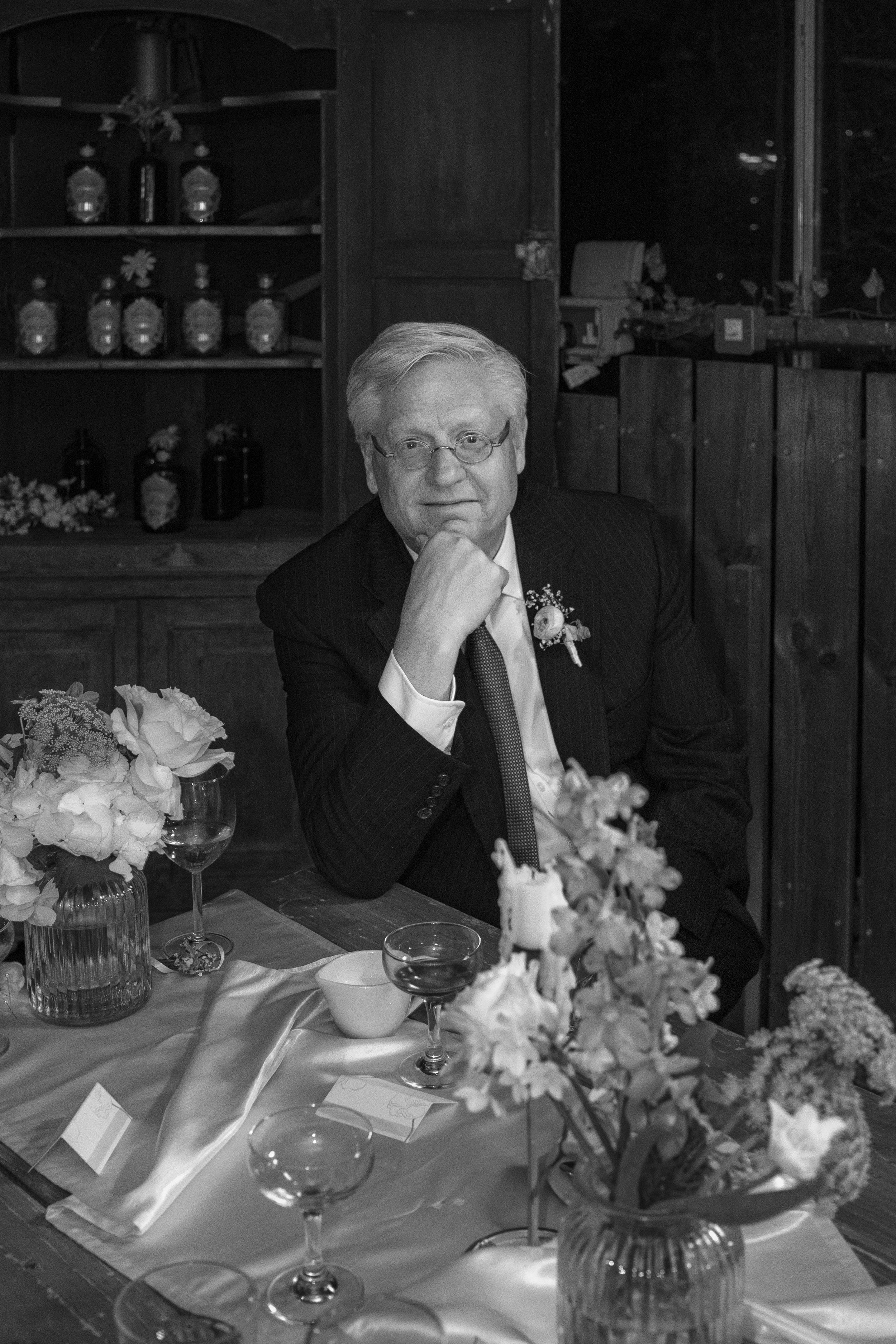 The father of the bride sitting at the table at the reception, looking contentedly into the camera