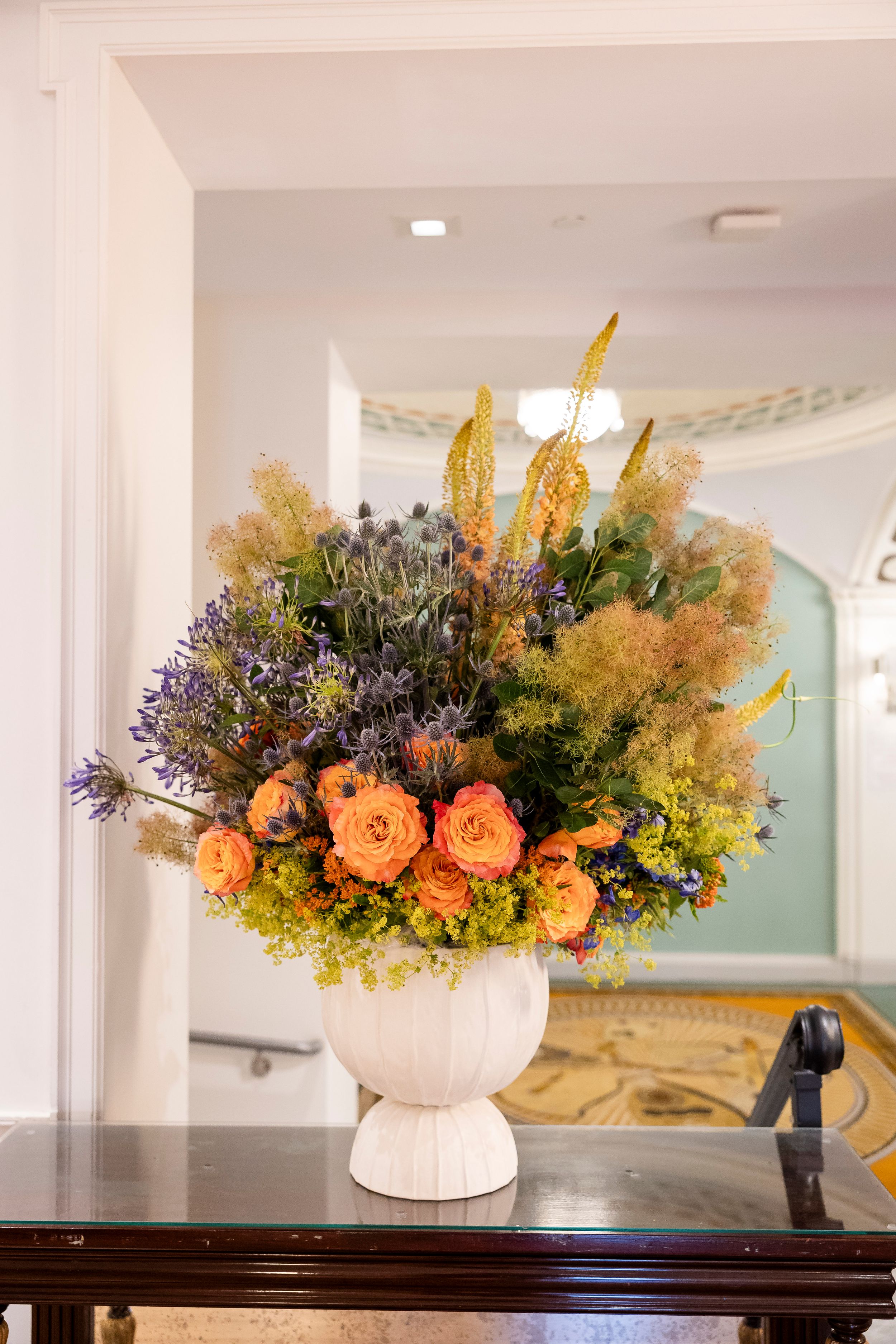 Decorative fall floral arrangements in white vases featuring orange roses and yellow accents.