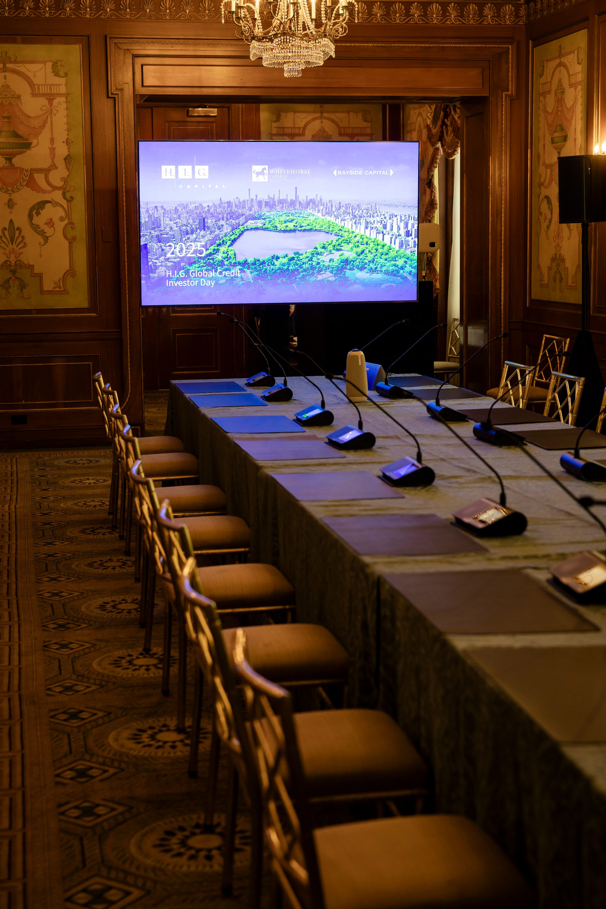 Corporate conference room setup with microphones and screens displaying presentation materials.